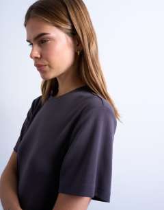Model wearing Slinky asymmetric short sleeve tunic top in charcoal grey