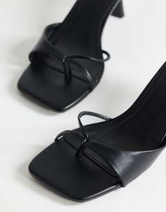 Model wearing Sophie asymmetric mid heel mule in black