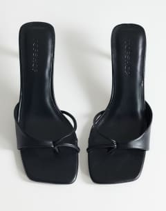 Model wearing Sophie asymmetric mid heel mule in black