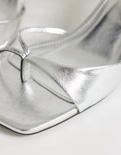 Model wearing Sophie asymmetric mid heel mule in silver