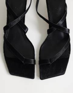 Model wearing Sophie strappy mid heel sandal in black print hair on real leather