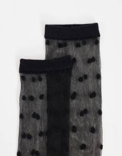 Model wearing Spot sheer knee-high socks in black