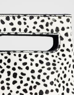 Model wearing Stella hair on real leather small grab bag in dalmatian print