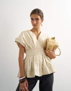 Model wearing Structured peplum top with pintucks in stone