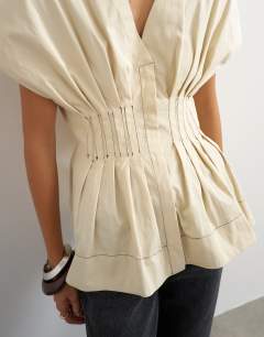 Model wearing Structured peplum top with pintucks in stone