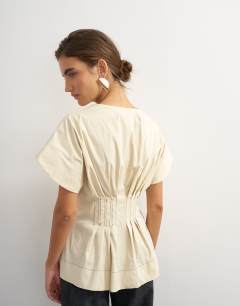 Model wearing Structured peplum top with pintucks in stone