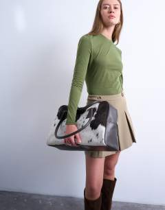 Model wearing Suki real leather shoulder bowler bag in cow print pony