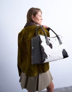 Model wearing Suki real leather shoulder bowler bag in cow print pony