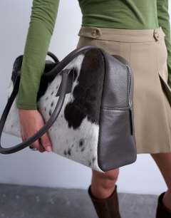 Model wearing Suki real leather shoulder bowler bag in cow print pony