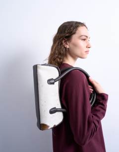 Model wearing Sullivan real leather shoulder bowler bag in cow print pony
