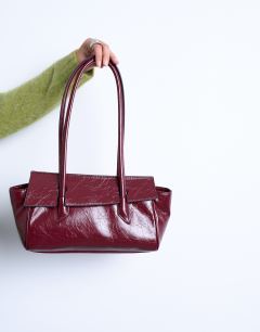 Model wearing Sunny shoulder bag with asymmetric flap in burgundy