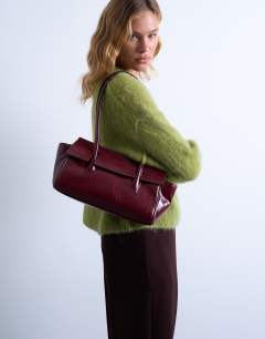 Model wearing Sunny shoulder bag with asymmetric flap in burgundy