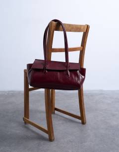 Model wearing Sunny shoulder bag with asymmetric flap in burgundy