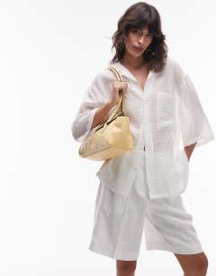 Model wearing Sunny shoulder bag with asymmetric flap in lemon