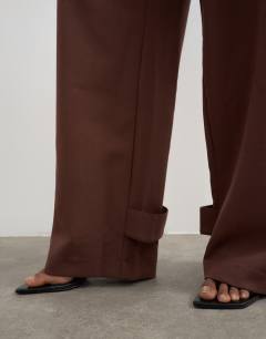 Model wearing Tailored barrel leg tab detail trouser in brown
