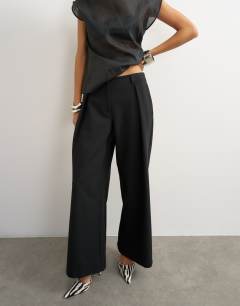 Model wearing Tailored pleat detail low rise wide leg trousers in black