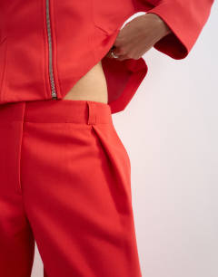 Model wearing Tailored pleat detail low rise wide leg trousers in red