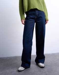Model wearing Tall Cinch low rise relaxed jean in raw look indigo