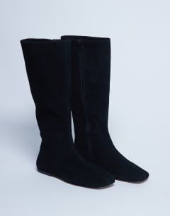 Model wearing Tess real suede knee high flat boot in black