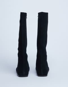 Model wearing Tess real suede knee high flat boot in black
