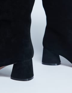 Model wearing Thea real suede knee high block heel boot in black