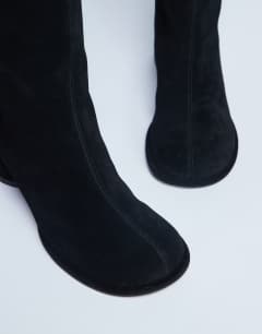 Model wearing Thea real suede knee high block heel boot in black