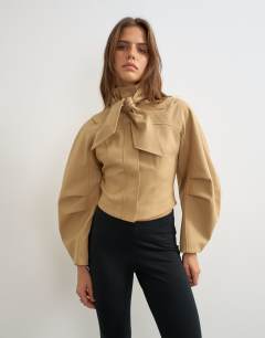 Model wearing Tie neck fitted ovoid sleeve jacket in beige