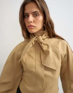 Model wearing Tie neck fitted ovoid sleeve jacket in beige