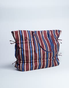 Model wearing Tino nylon ruched tote bag in burgundy stripe