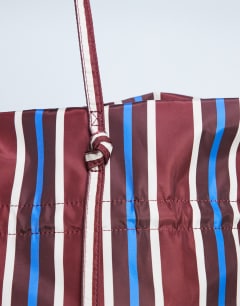 Model wearing Tino nylon ruched tote bag in burgundy stripe