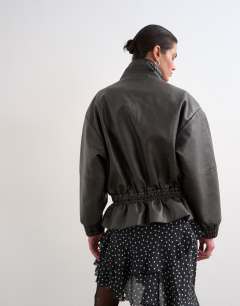 Model wearing Toggle waist leather look funnel zip through jacket in black