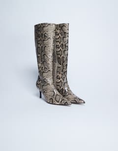 Model wearing Tori knee high point toe boot in snake