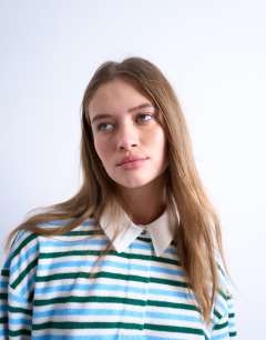 Model wearing Towelling stripe polo in blue and green