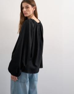 Model wearing Trapeze linen tie front blouse in black