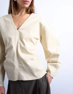 Model wearing V neck ovoid sleeve top in cream
