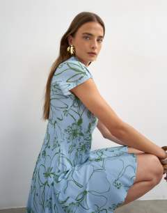 Model wearing Viscose grown on sleeve dress in blue and green sketchy floral