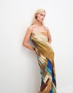 Model wearing Viscose satin low scoop flood length maxi slip dress in abstract ochre print