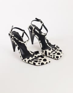 Model wearing Willow T bar banana heel sandal in dalmatian hair on real leather