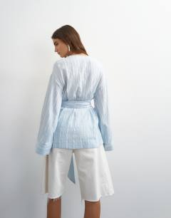 Model wearing Wrap tie detail top in blue stripe
