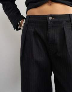 Model wearing X Cara wide leg pleated pinstripe denim co-ord trouser in indigo
