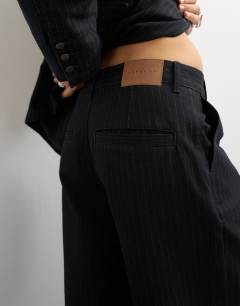 Model wearing X Cara wide leg pleated pinstripe denim co-ord trouser in indigo