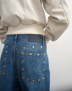 Model wearing Topshop x Talia Byre straight leg studded jeans in washed blue