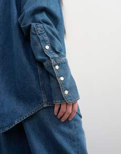 Model wearing Topshop x Talia Byre wide placket studded shirt in washed blue