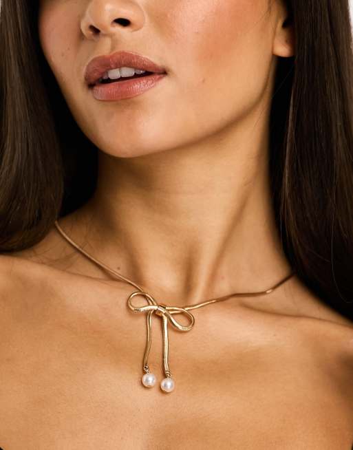 True Decadence – Goldfarbene Halskette mit Schleifendesign und Kunstperlen