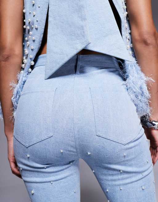 Vaqueros azules con bajos de plumas sintéticas y diseño adornado