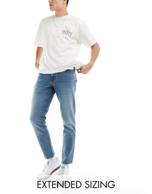 Vaqueros azules elásticos de corte tapered con lavado tintado medio de ASOS DESIGN 