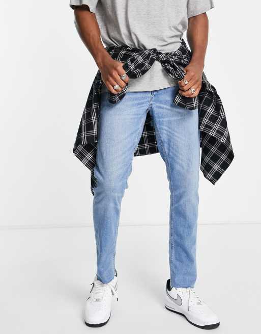 Vaqueros elásticos azul medio lavado de corte slim con bajos sin rematar de ASOS DESIGN