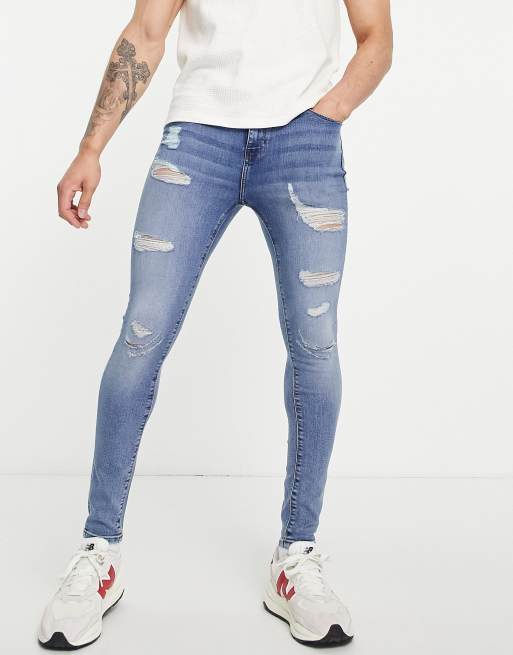 Vaqueros superajustados elásticos con lavado azul medio y roturas extremas de ASOS DESIGN