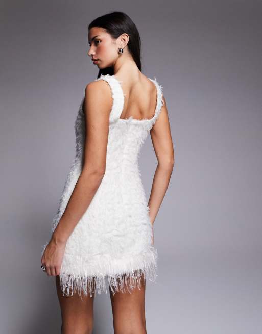 Vestido blanco de punto con botones adornados y ribete de plumas