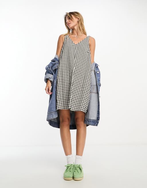 Vestido corto a cuadros vichy negros y blancos con bolsillos laterales y tirantes anudados de sirsaca de Monki